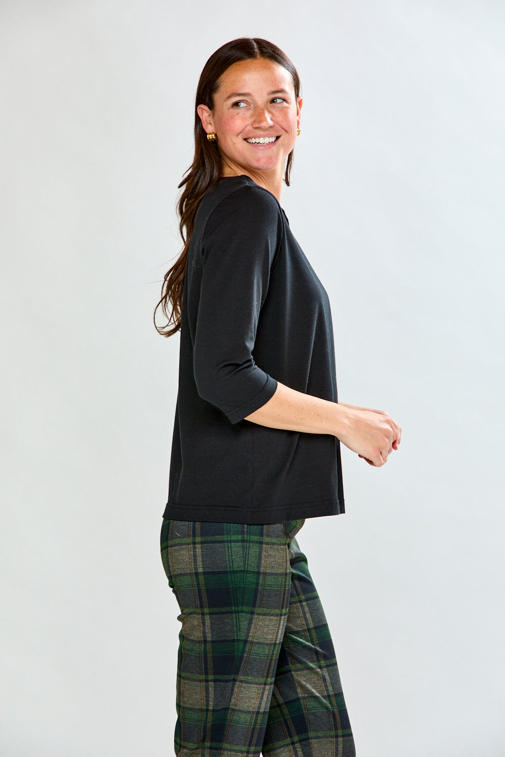 Woman wearing a black top and plaid pants on a white background