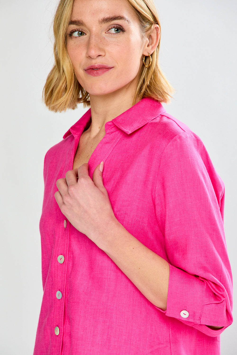 Woman wearing a bright pink shirt against a white background