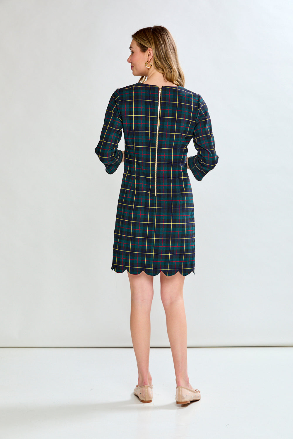 Woman wearing a plaid dress against a plain background