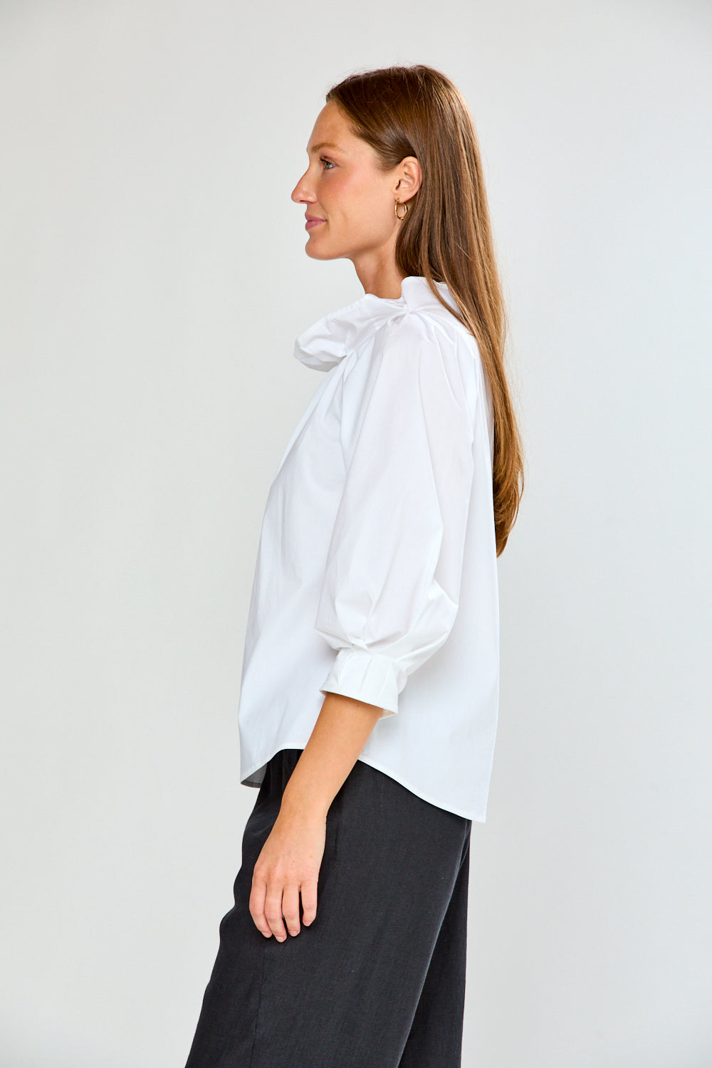 Woman wearing a white blouse with puffed sleeves against a plain background