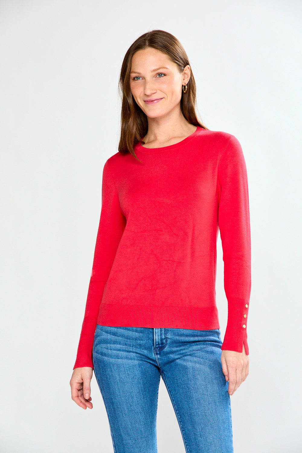 Woman wearing a pink sweater and light blue jeans on a white background