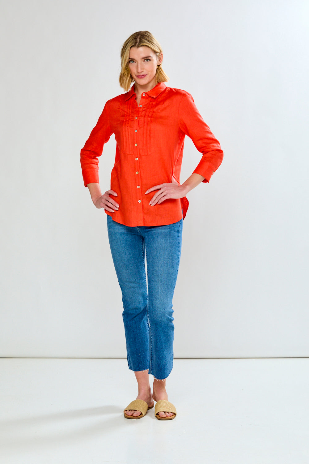 Woman wearing a bright orange shirt and blue jeans on a white background