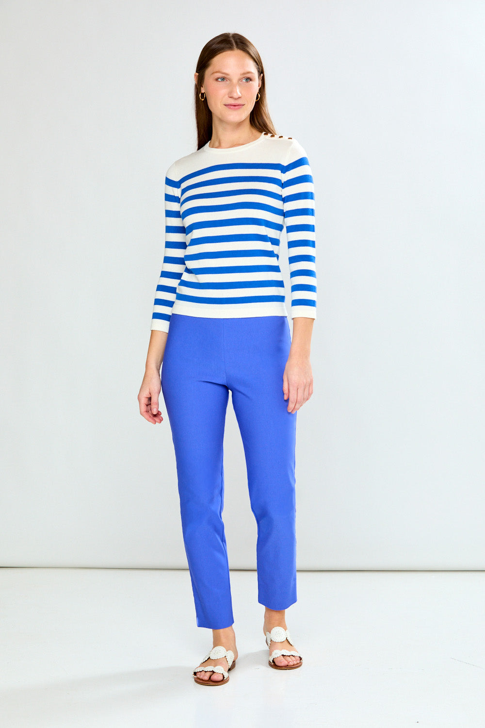 Woman wearing a blue and white striped sweater and blue pants against a white background