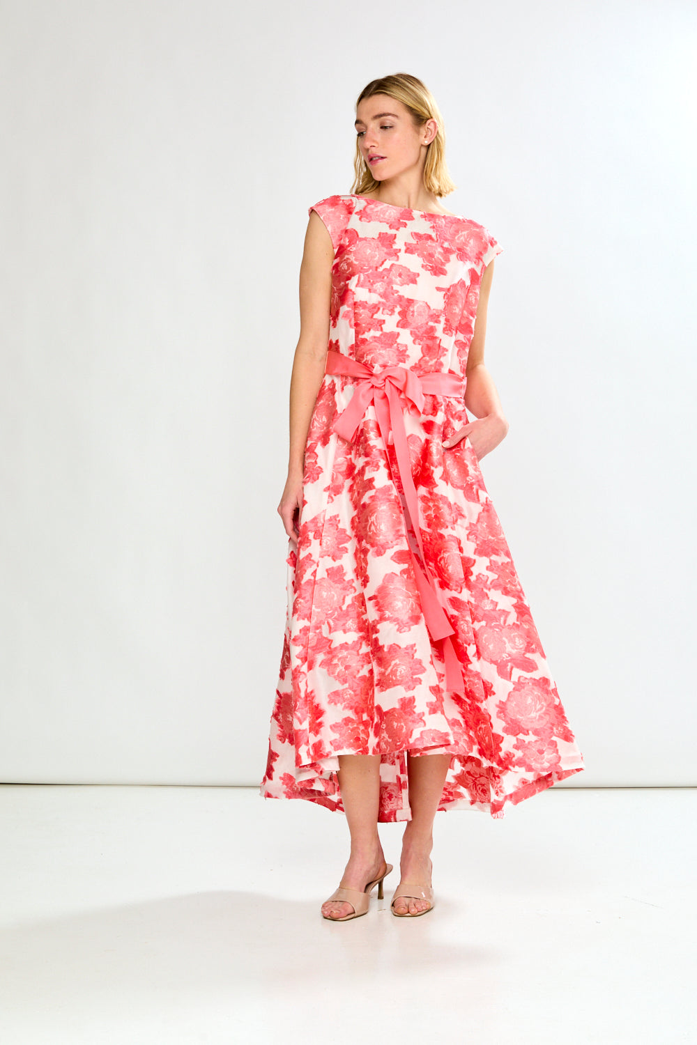 Woman wearing a pink and white floral dress on a white background