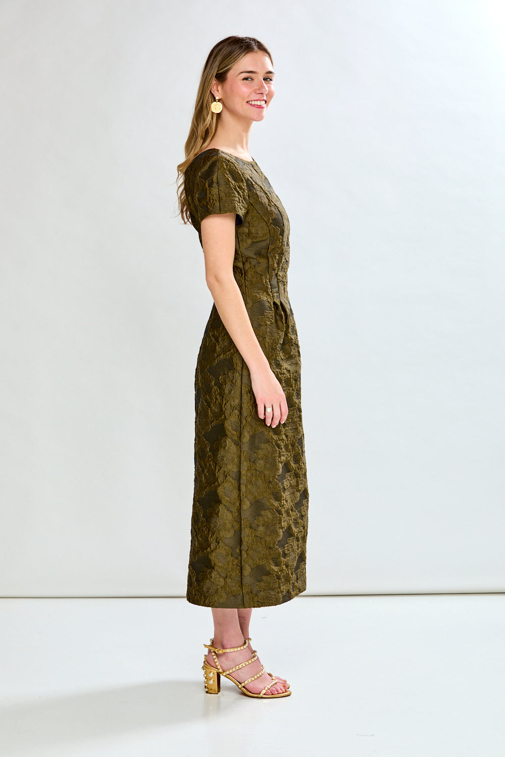 Woman wearing a green dress with a subtle pattern on a white background