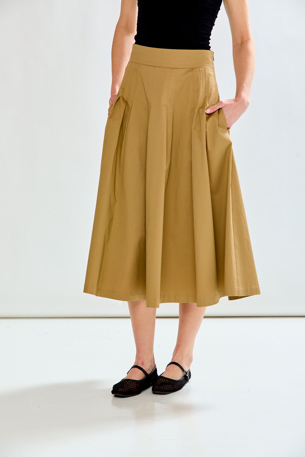 Person wearing a beige skirt and black top on a white background