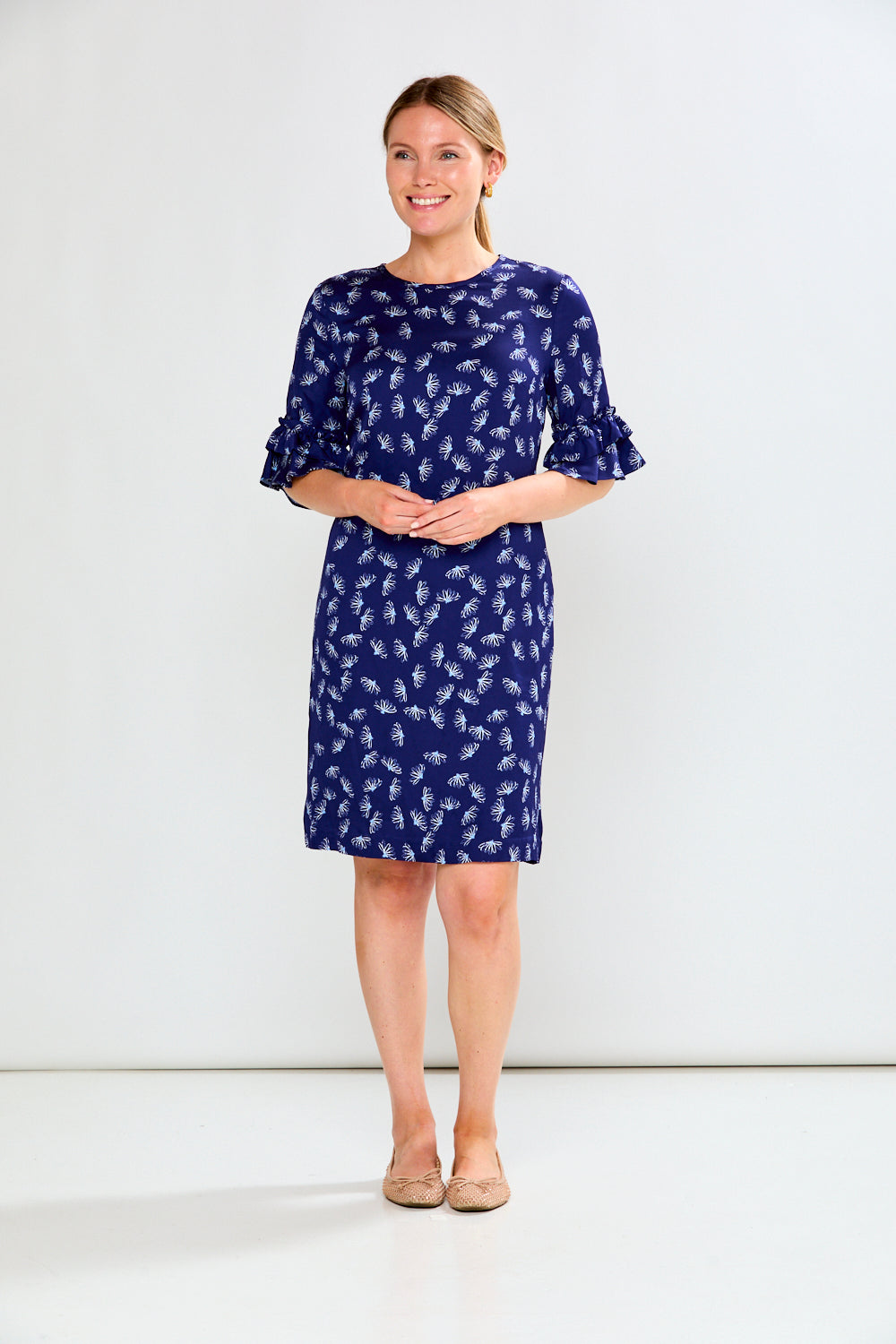 Woman wearing a blue dress with white floral pattern on a white background