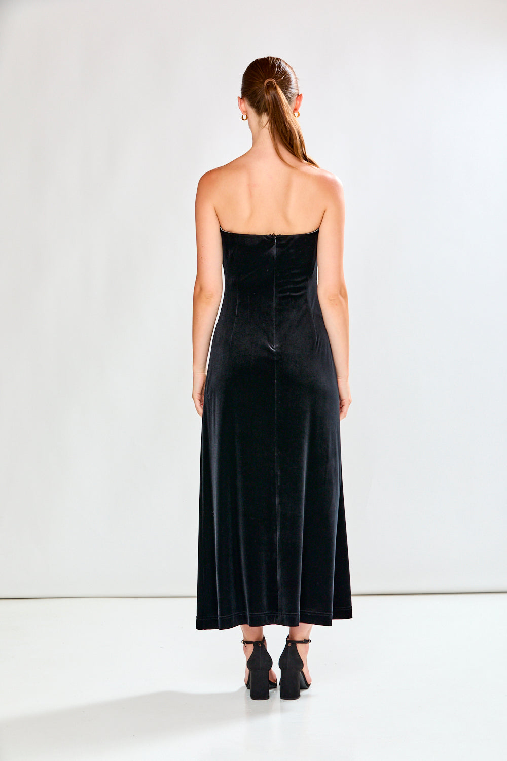 Woman wearing a black strapless dress against a white background