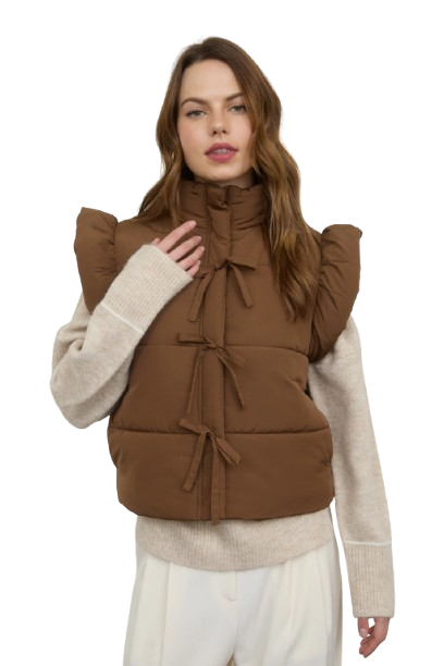 Woman wearing a brown puffer vest over a beige sweater on a white background