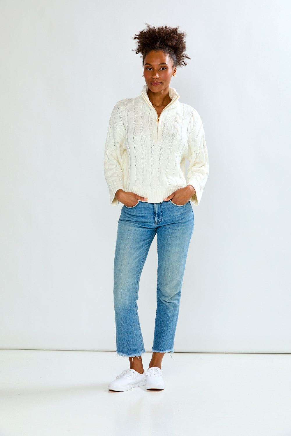 Person wearing a light-colored shirt and blue jeans against a white background
