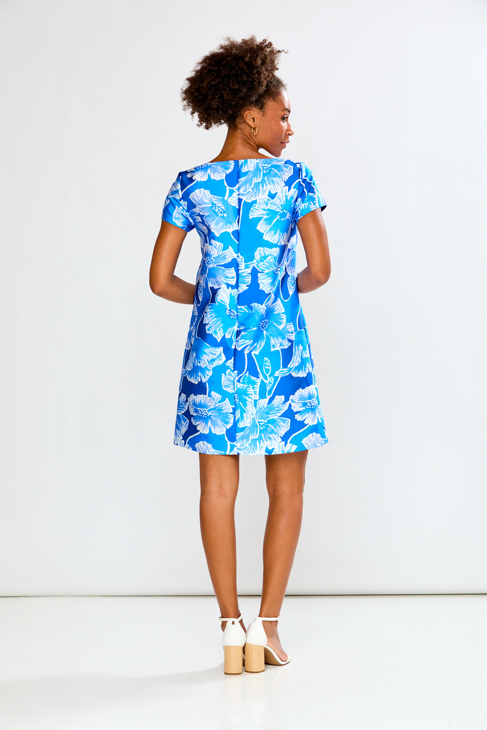 Woman wearing a blue floral dress against a white background
