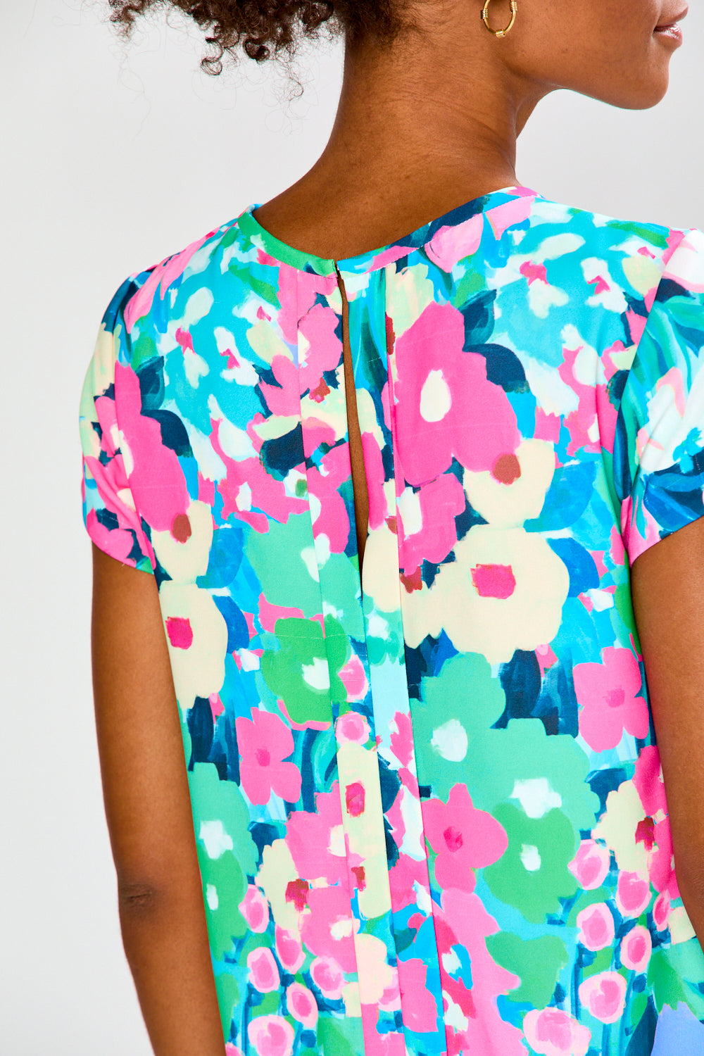 Colorful floral-patterned top worn by a person on a white background