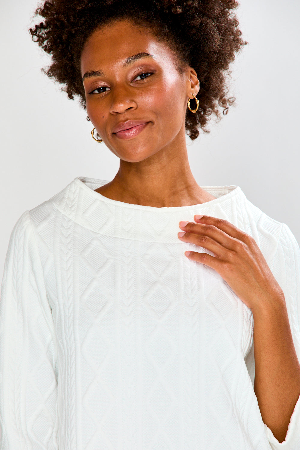 Woman wearing a white top and pink pants on a plain background