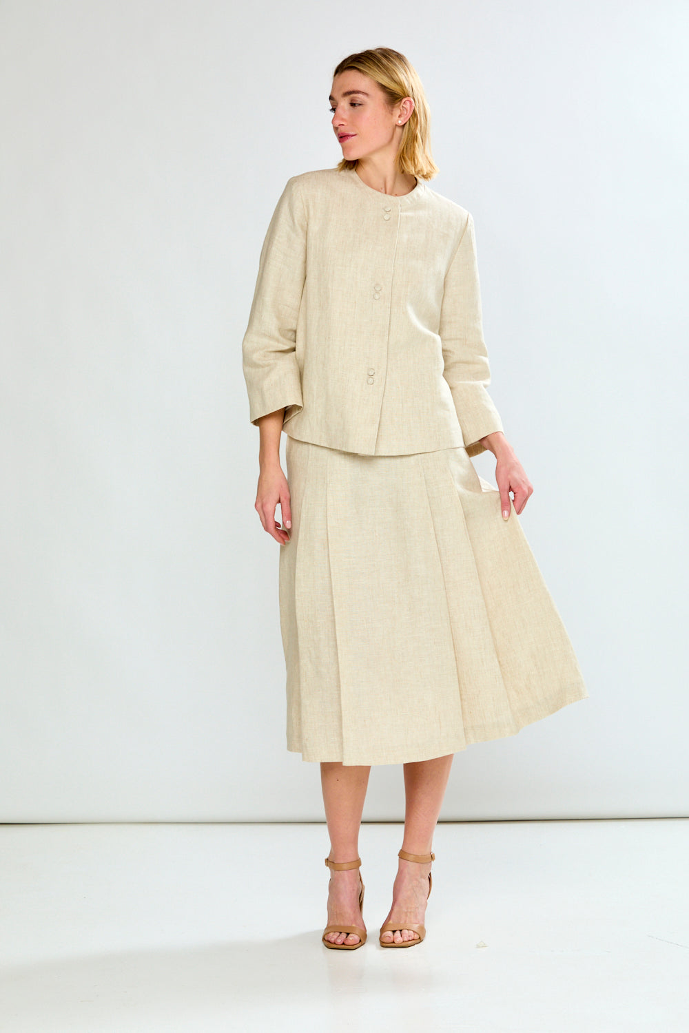 Woman wearing a beige suit with a jacket and skirt on a white background