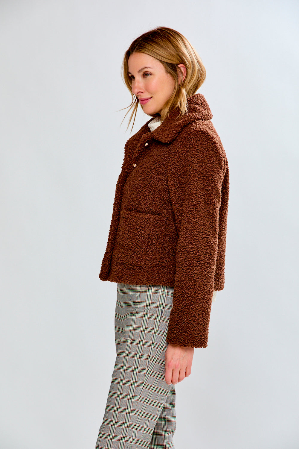 Woman wearing a brown teddy coat against a white background