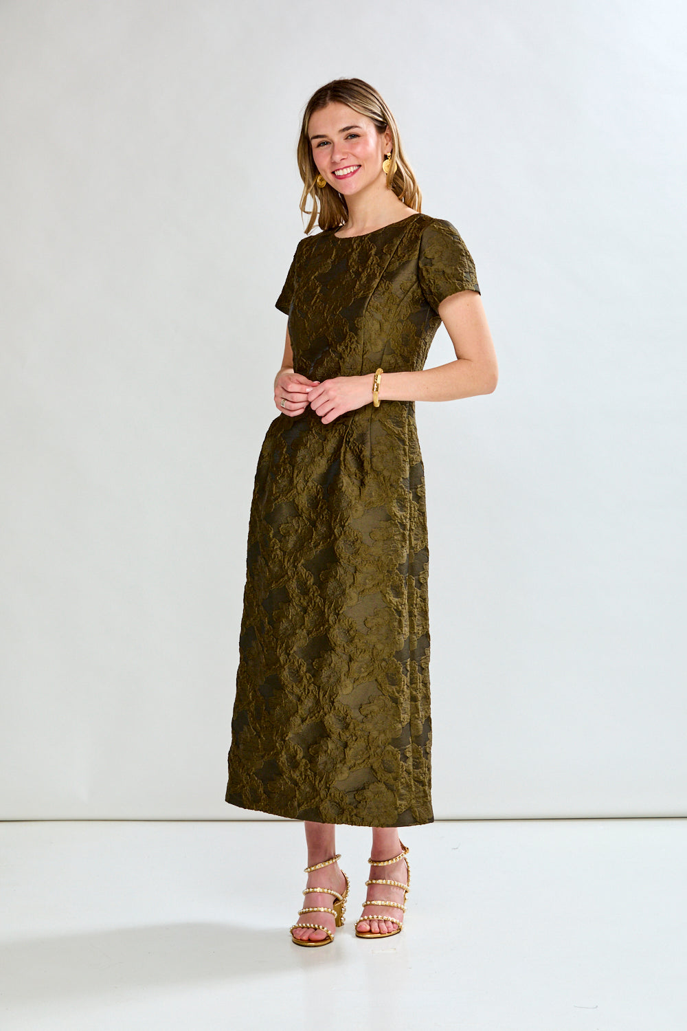 Woman wearing a green dress with a subtle pattern on a white background