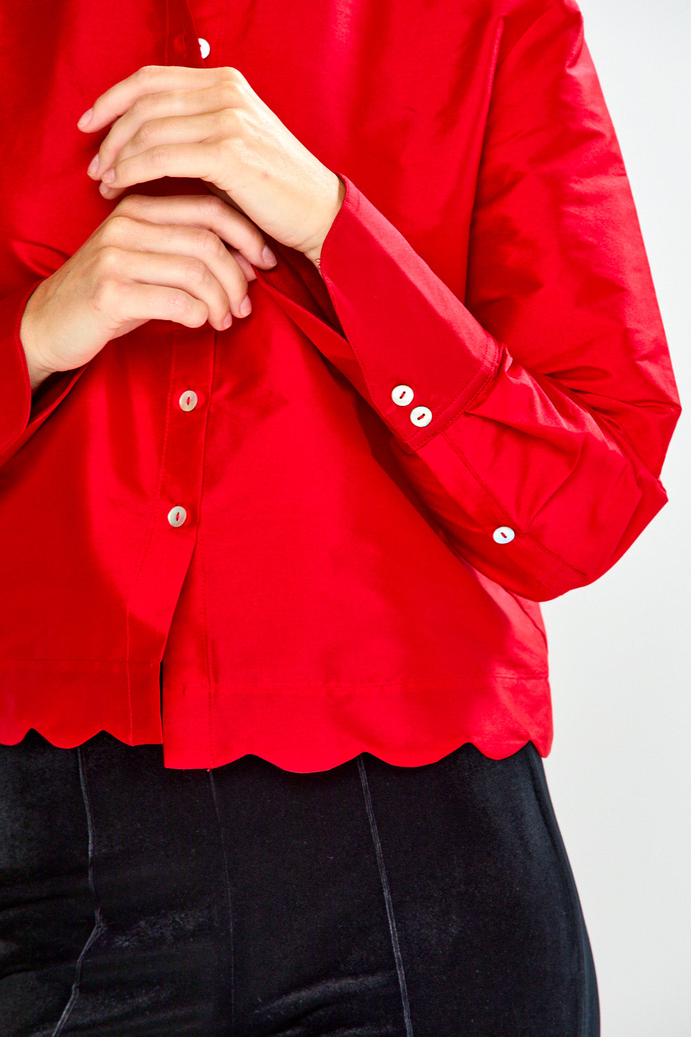 Woman wearing a red blouse and black pants on a white background