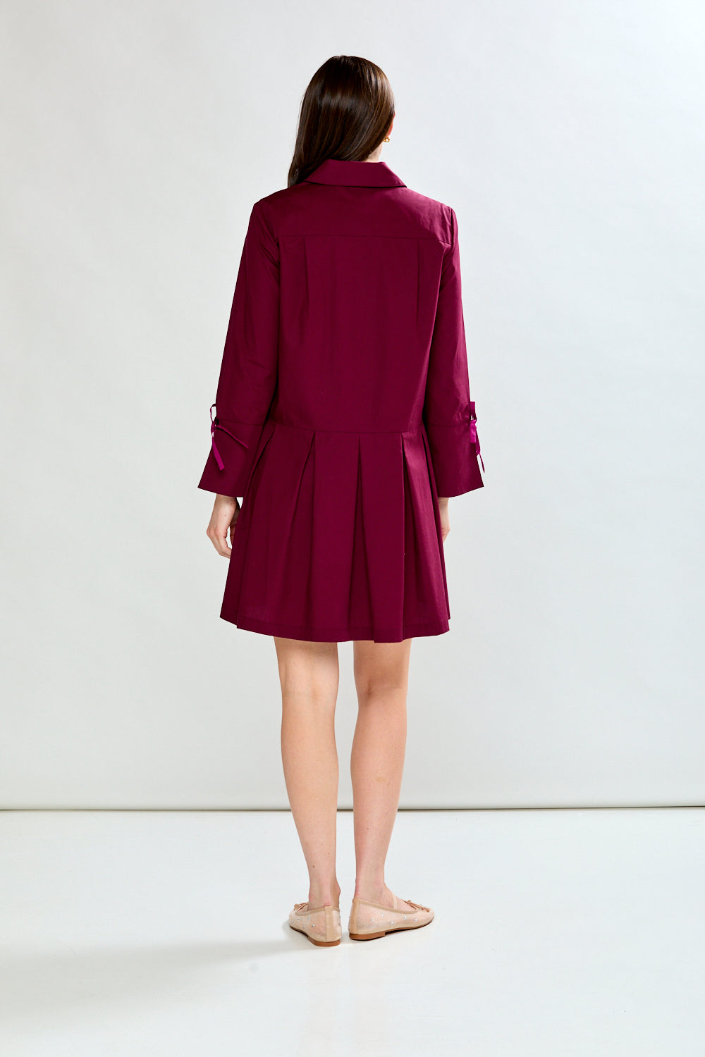 Woman wearing a raisin dress with long sleeves on a white background
