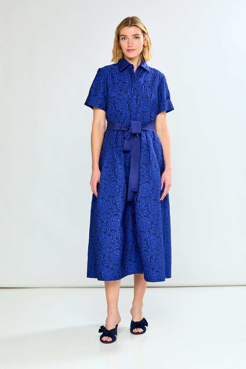 Woman wearing a blue dress with a belt on a white background