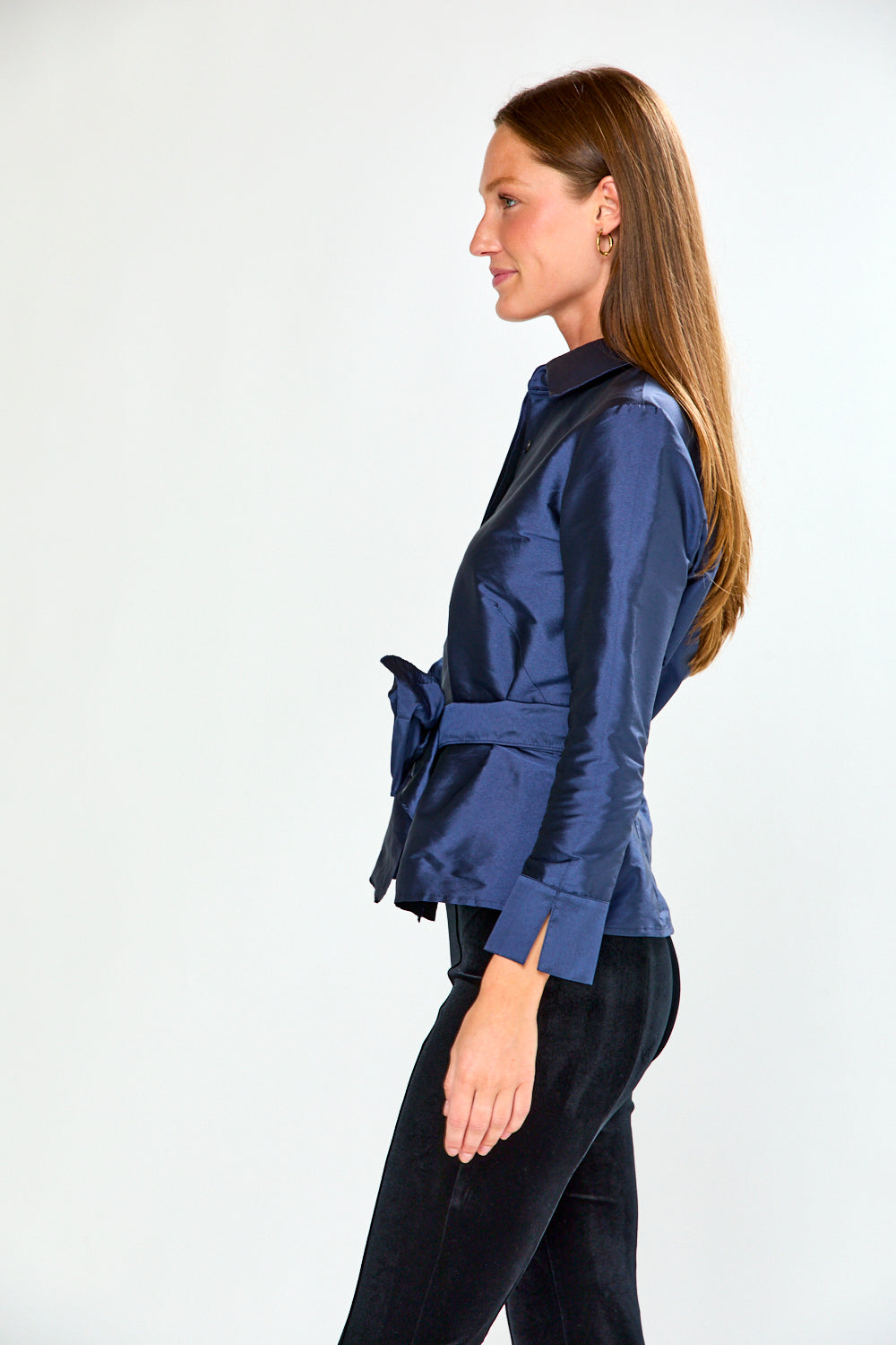 Woman wearing a blue blouse with a bow detail on a white background