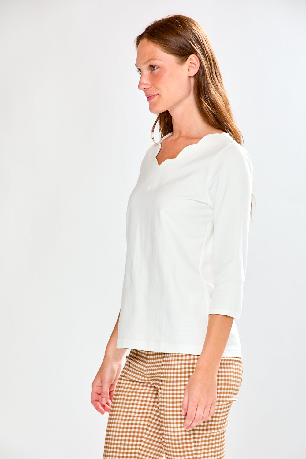 Woman wearing a white blouse and checkered pants on a plain background