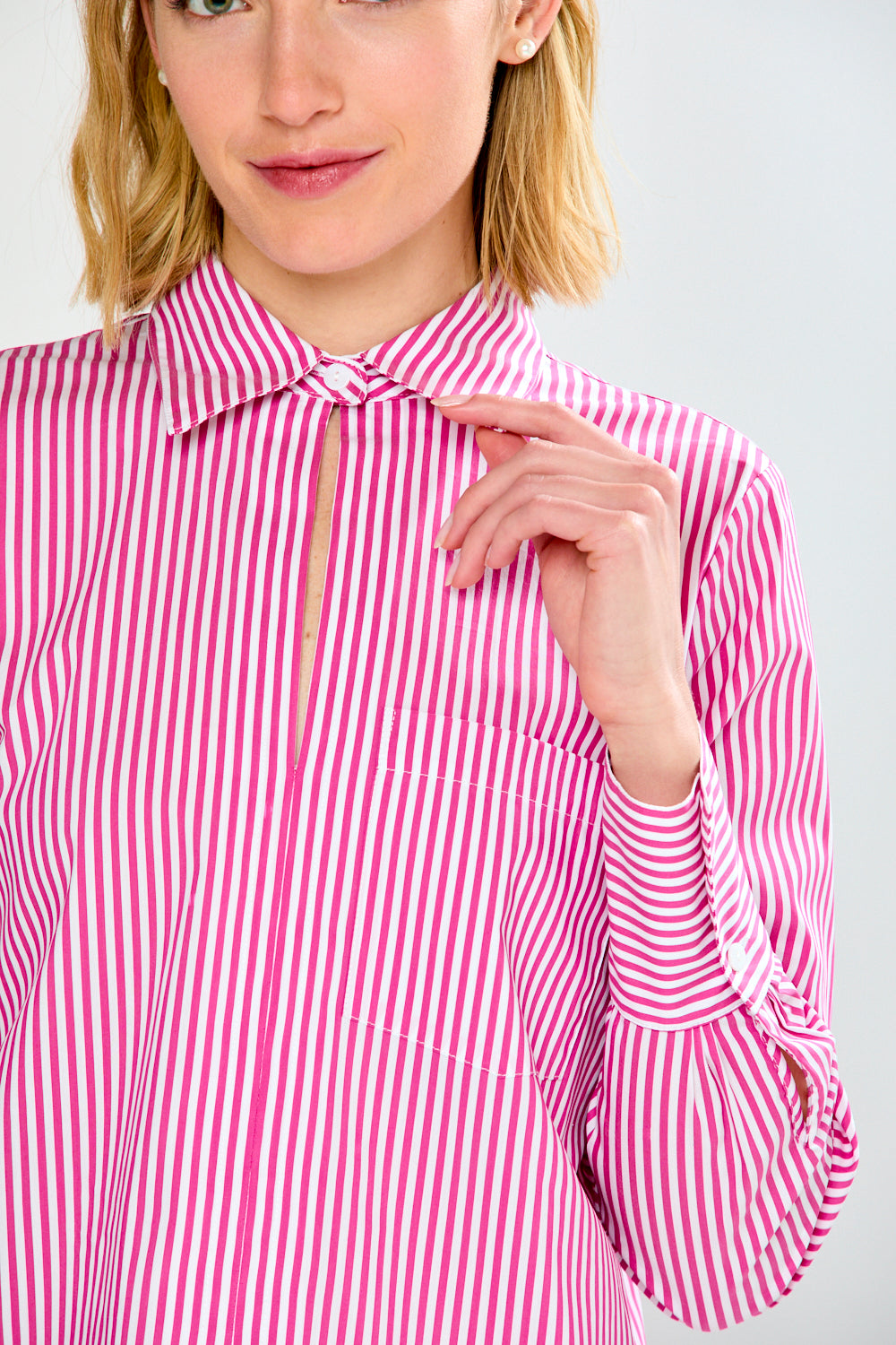 Woman wearing a pink and white striped shirt against a plain background
