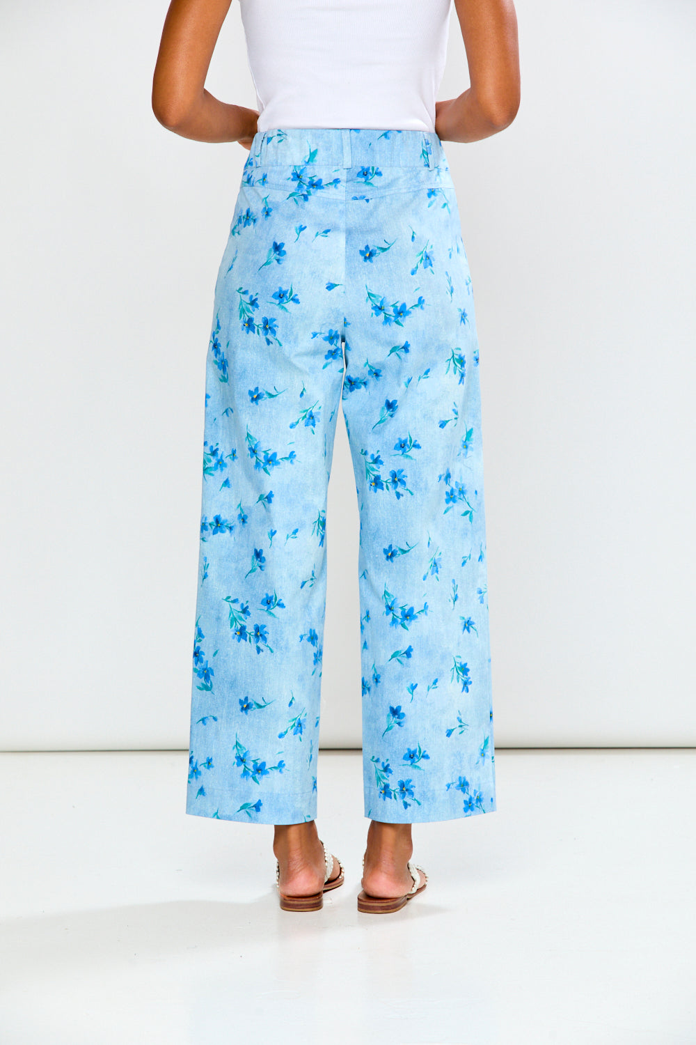 Person wearing light blue floral pants on a white background