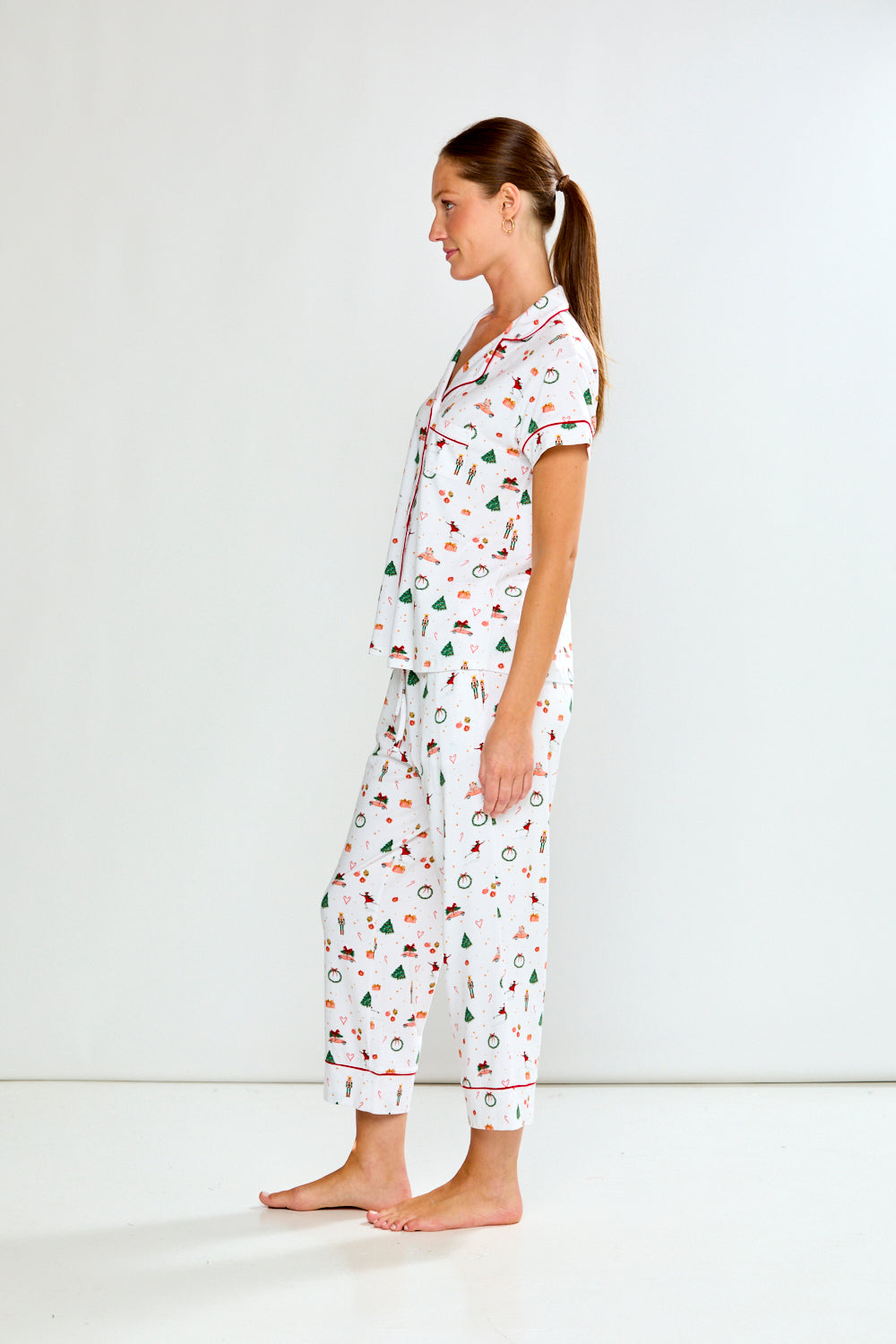 Woman wearing a white pajama set with colorful patterns on a white background