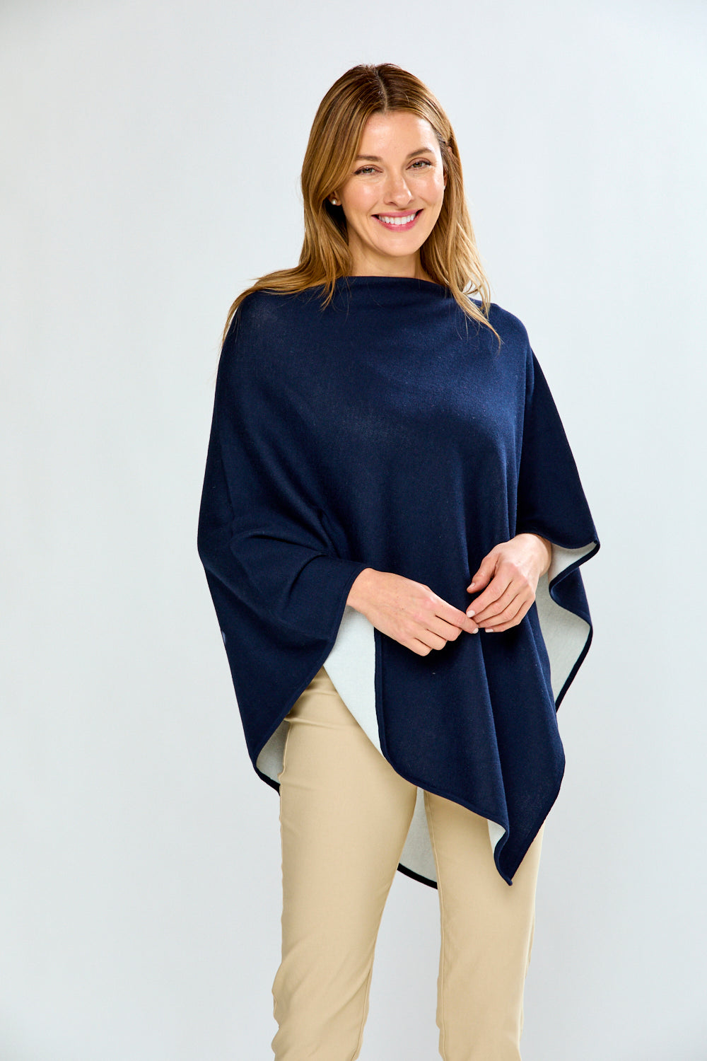 Woman wearing a navy blue poncho over a white background