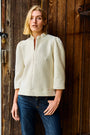 Woman wearing a textured white shirt and blue jeans 