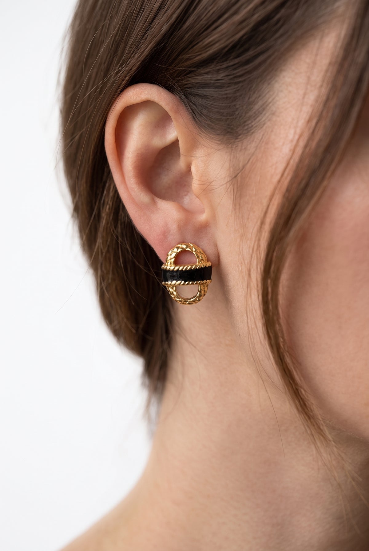 Woman wearing black and gold basket studs