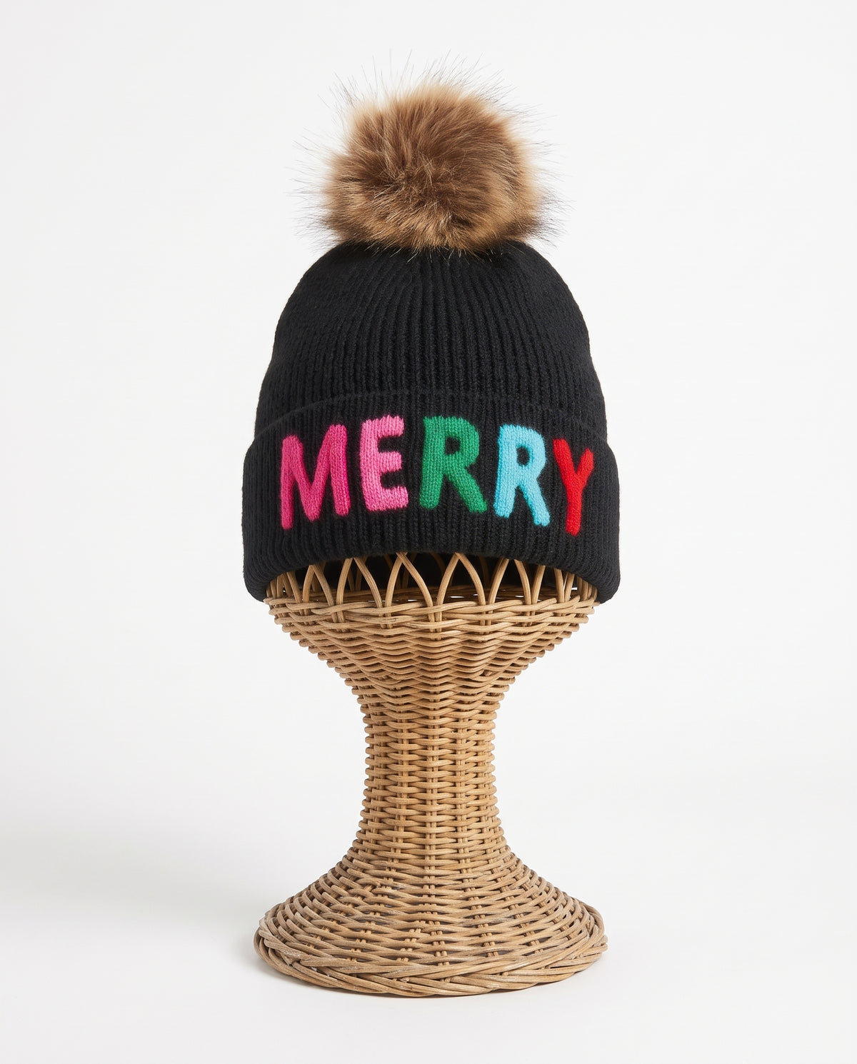 Black hat with "merry" written on it and a faux fur pom pom