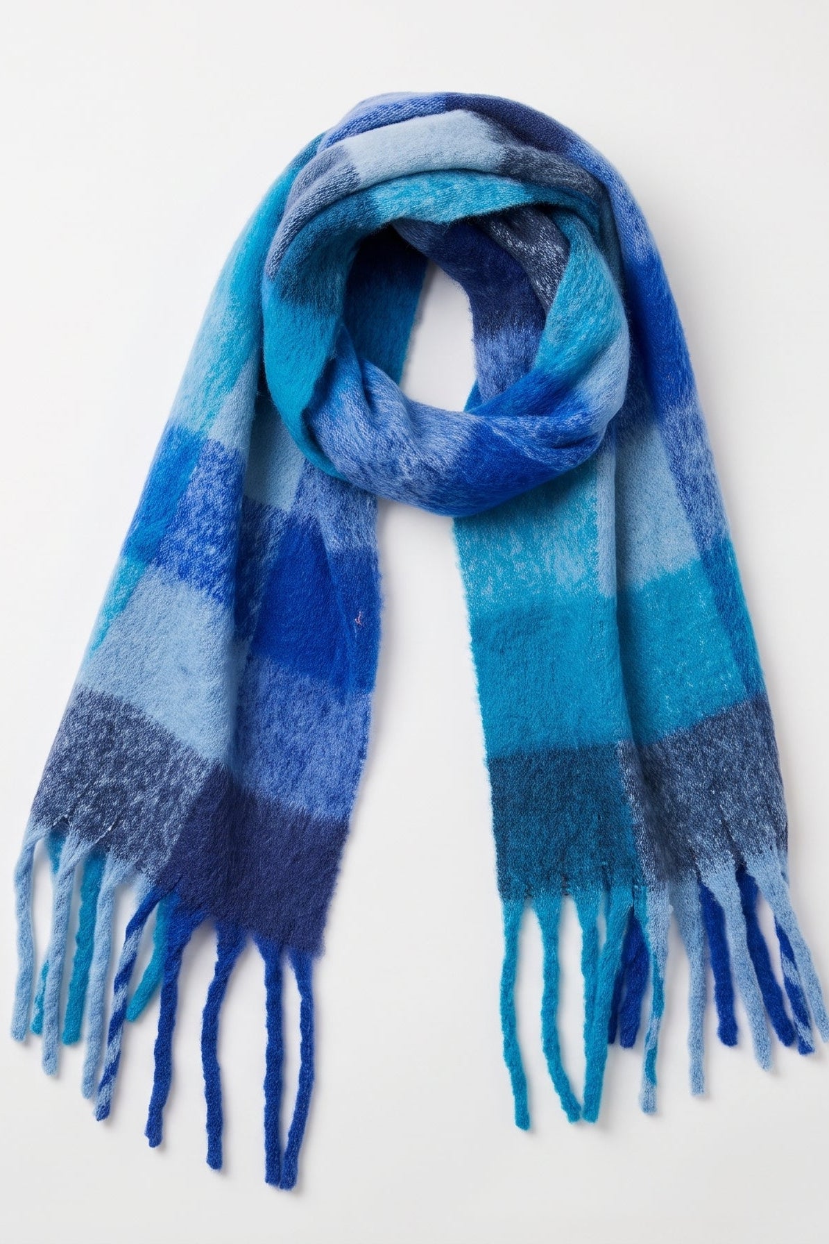 A soft woven scarf with a striped pattern in shades of blue, from light sky blue to deep navy, featuring fringed ends, displayed against a clean white background.