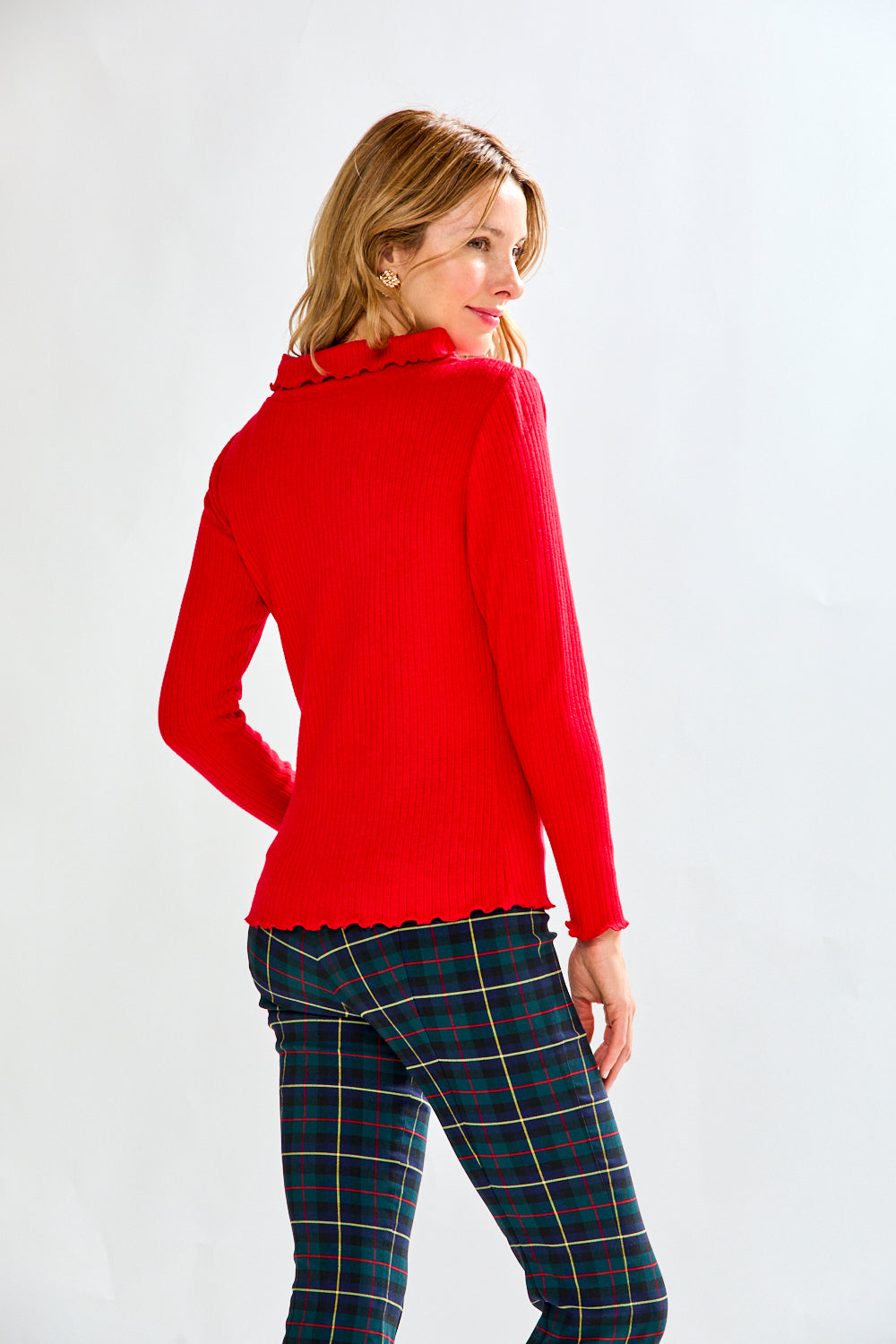 Woman wearing a red sweater and plaid pants on a white background