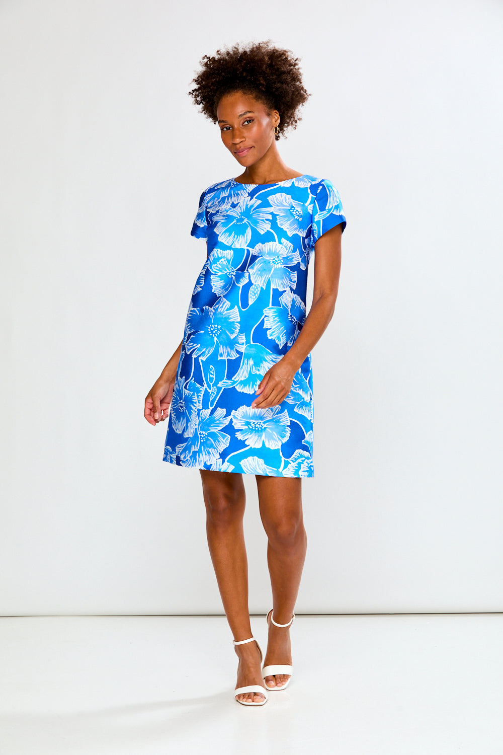 Woman wearing a blue floral dress against a white background