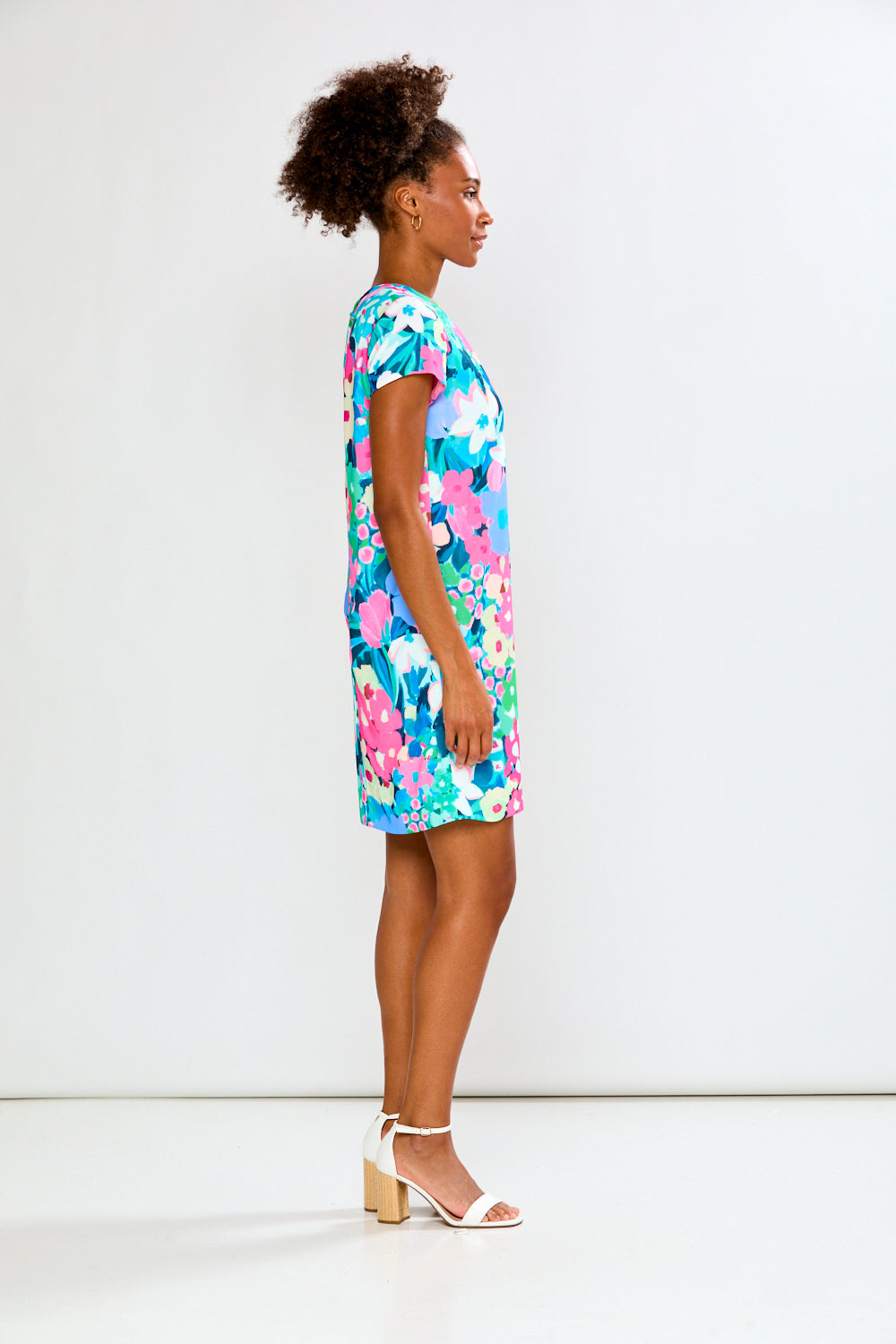 Woman wearing a colorful floral dress against a white background