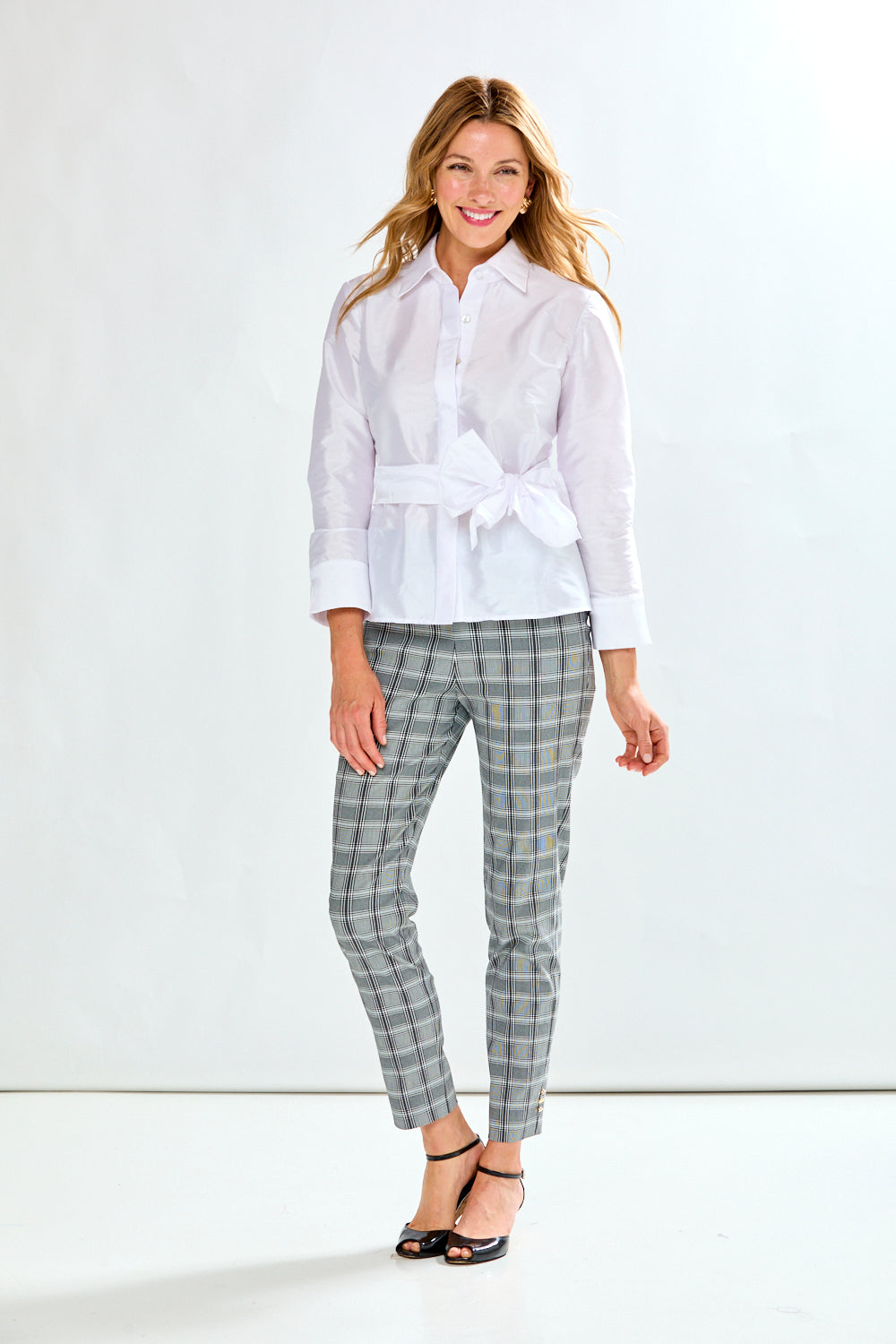 Woman wearing a white blouse and checkered pants on a white background