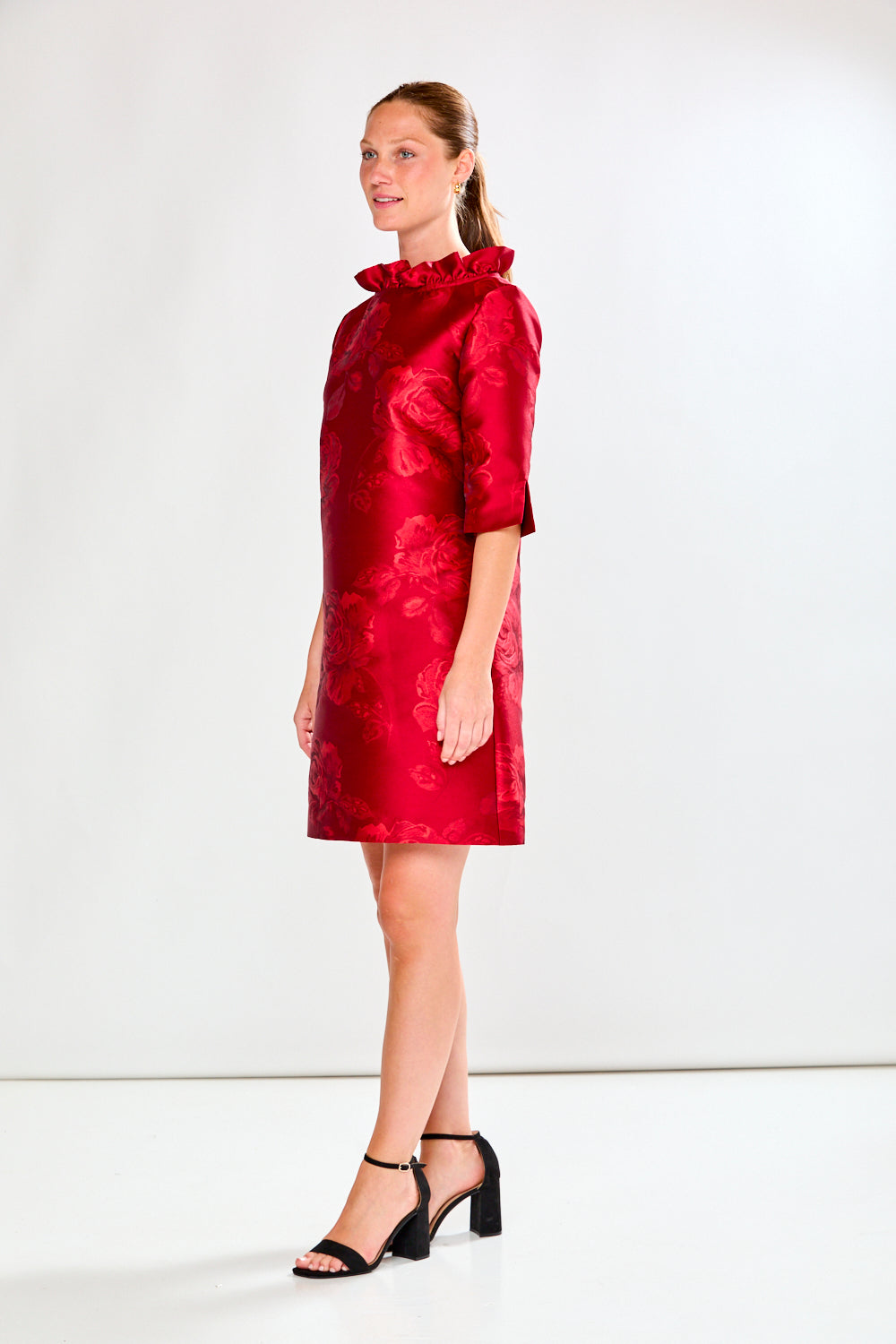 Woman wearing a red dress with floral pattern on a white background