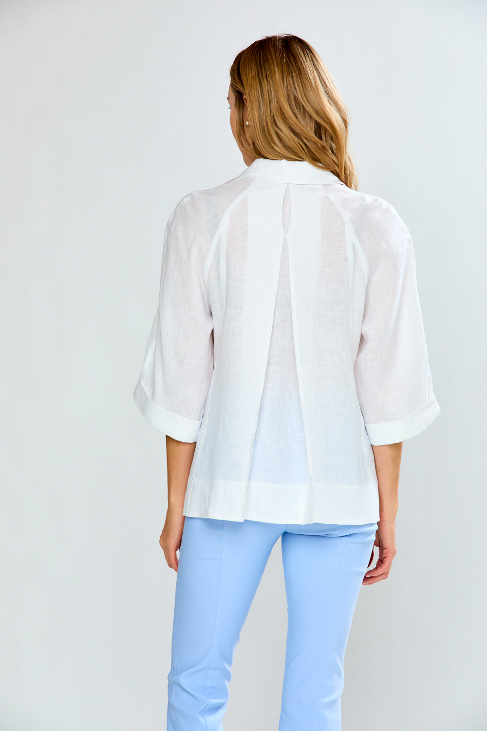 Person wearing a white blouse and light blue pants on a plain background