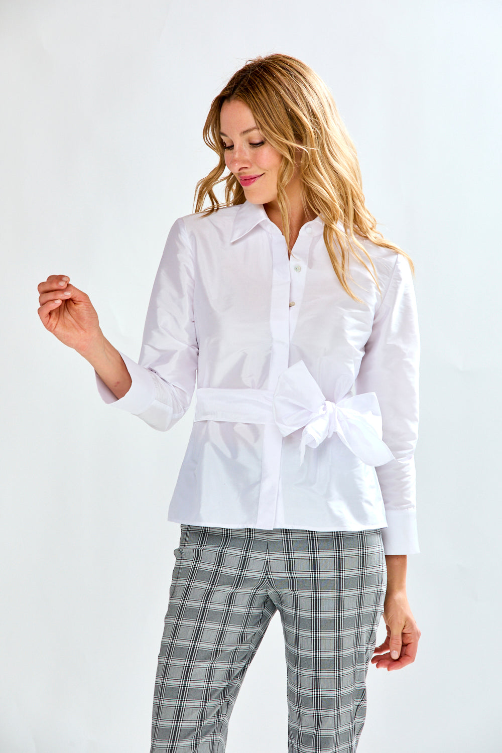 Woman wearing a white blouse and checkered pants on a white background