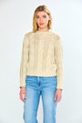 Woman wearing a pebble cable knit sweater and blue jeans on a white background