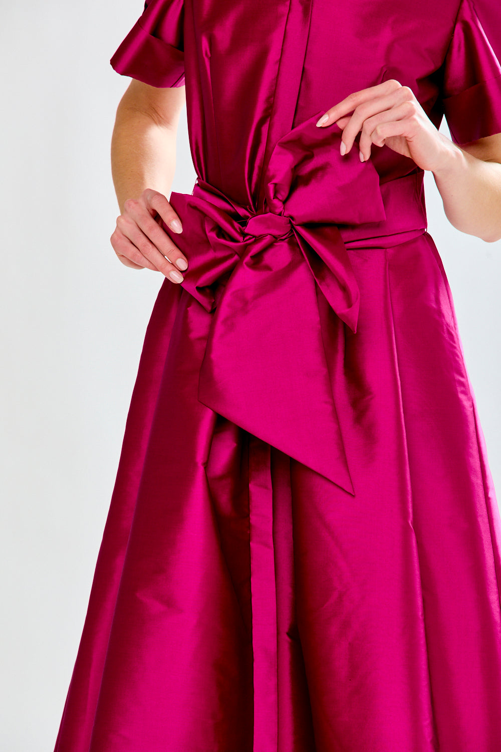 Fuchsia dress with a large bow detail on a white background