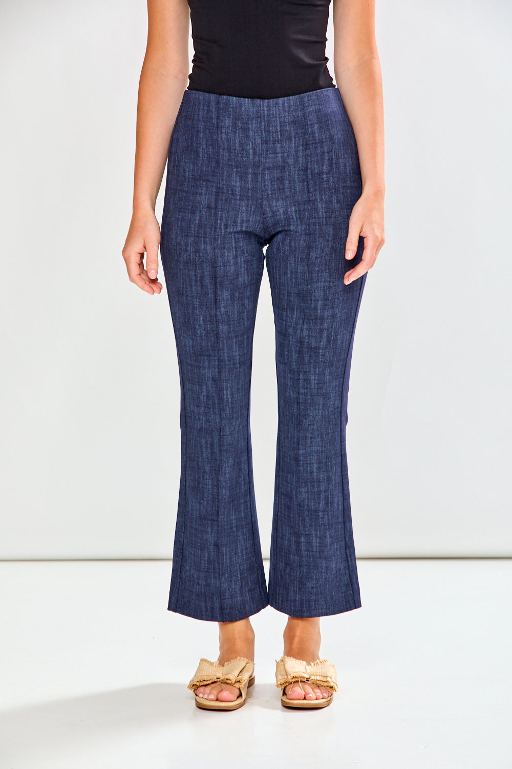 Person wearing blue flared pants and a black top on a white background