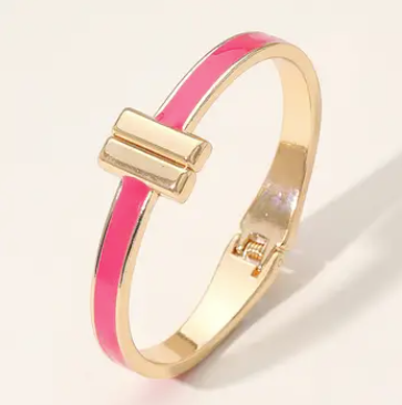 Gold bracelet with a pink band on a light background