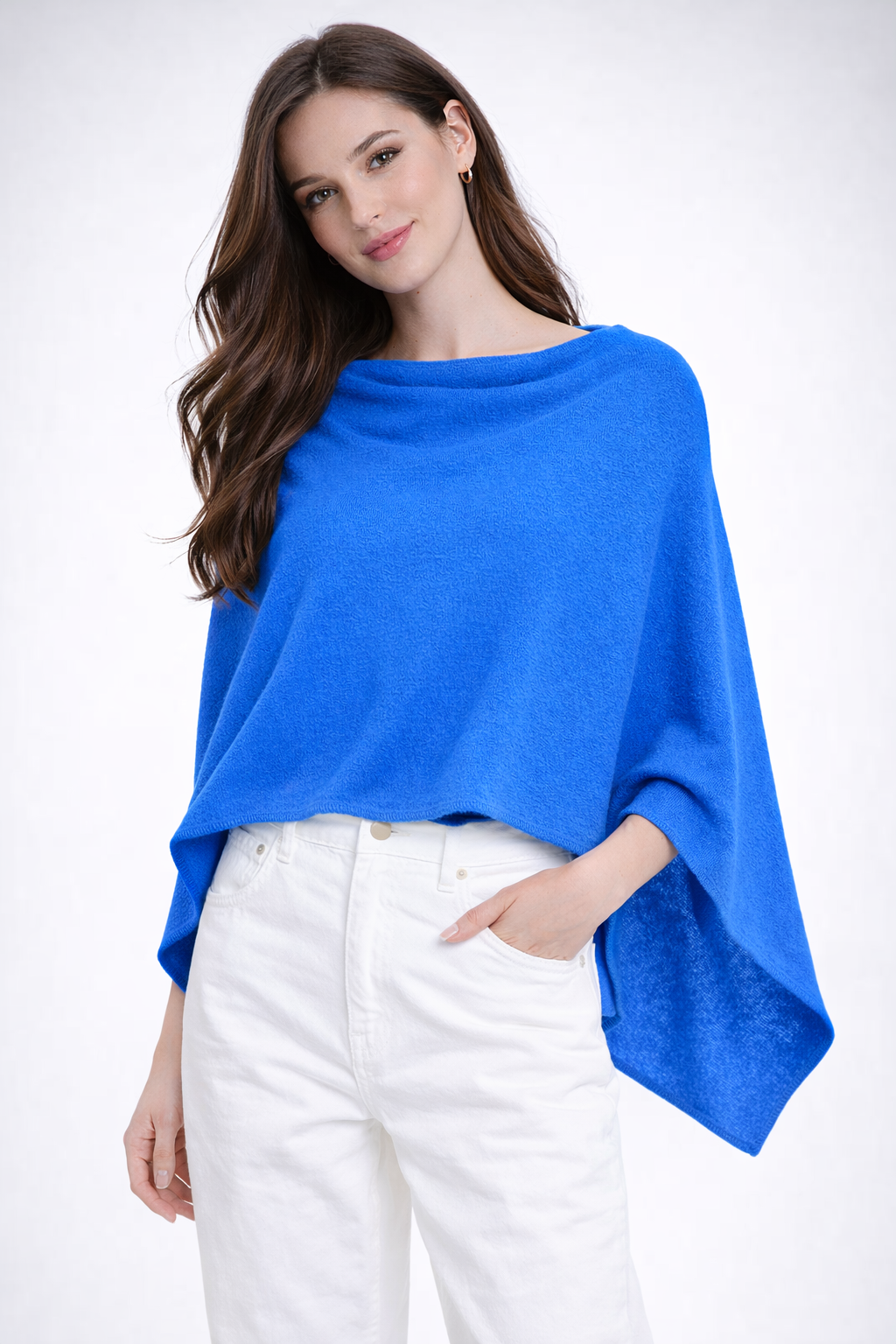 Woman wearing a blue poncho over a white outfit on a white background