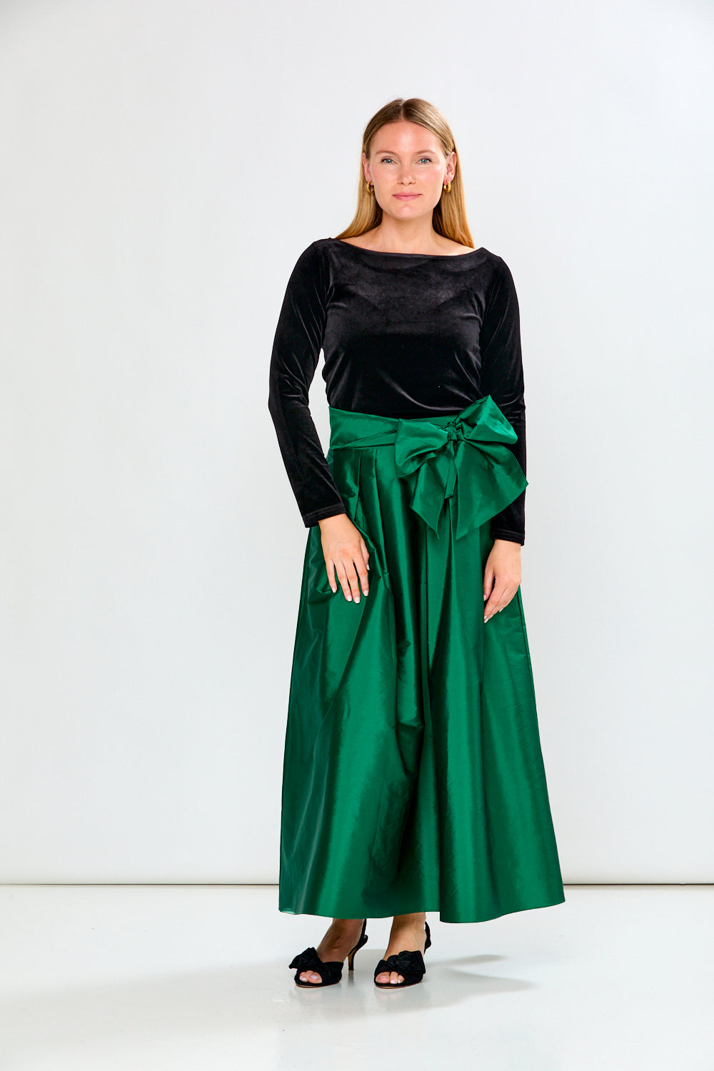 Woman wearing a Black top and Emerald skirt on a white background
