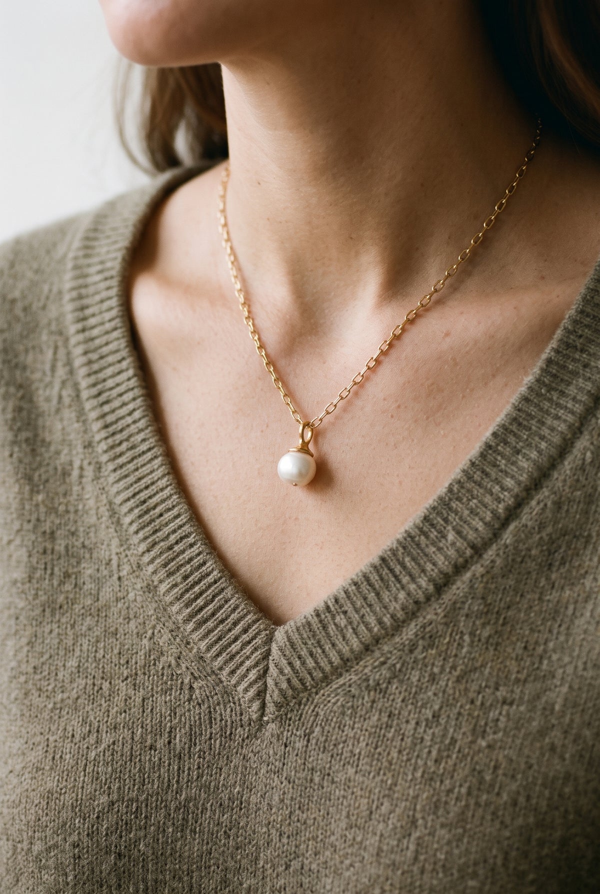 Woman earing a gold pearl pendant necklace