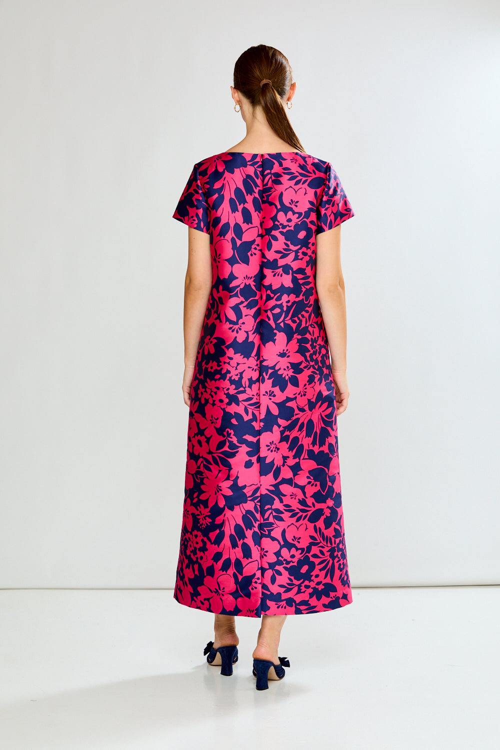 Woman wearing a pink and blue floral dress on a white background