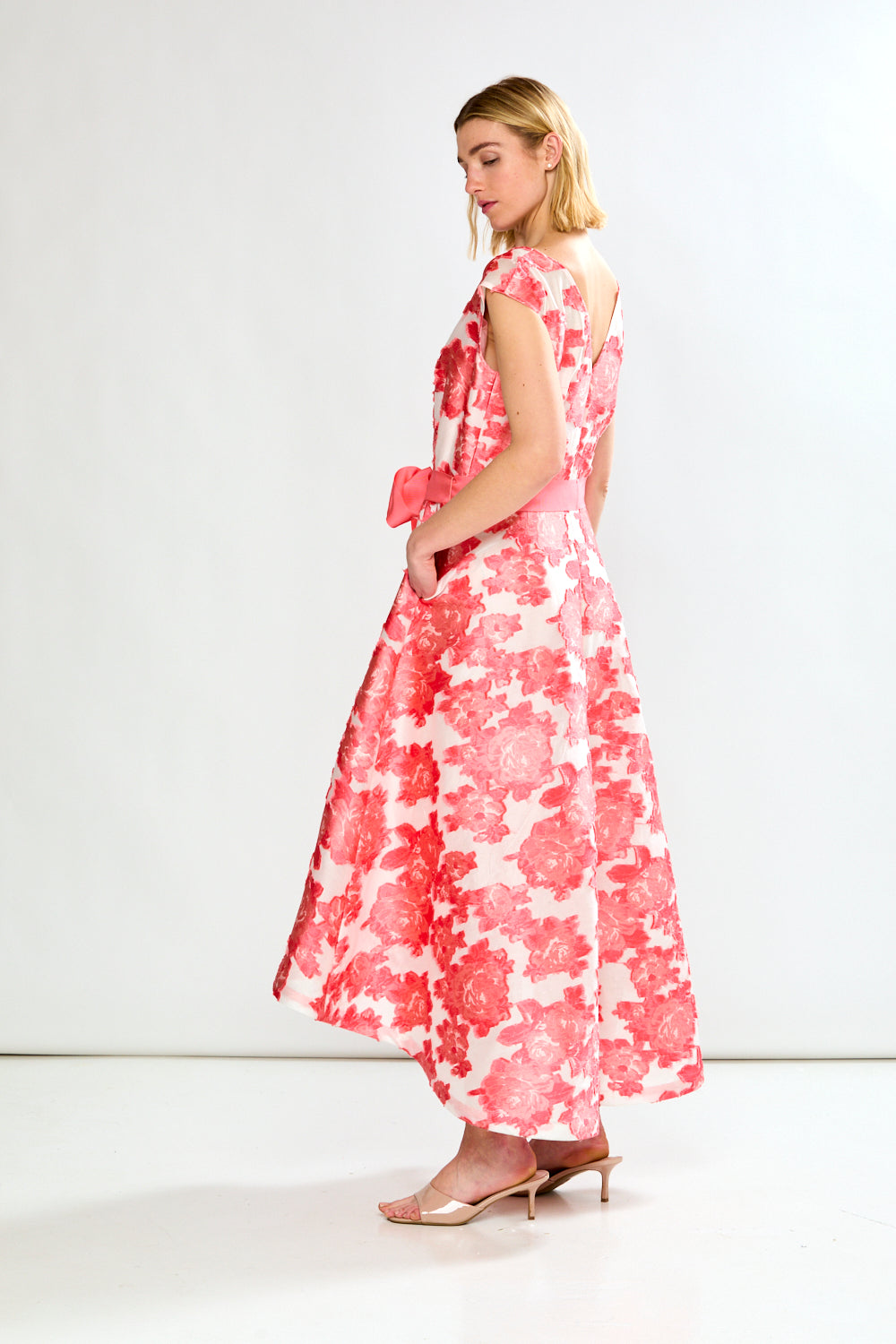 Woman wearing a pink and white floral dress on a white background