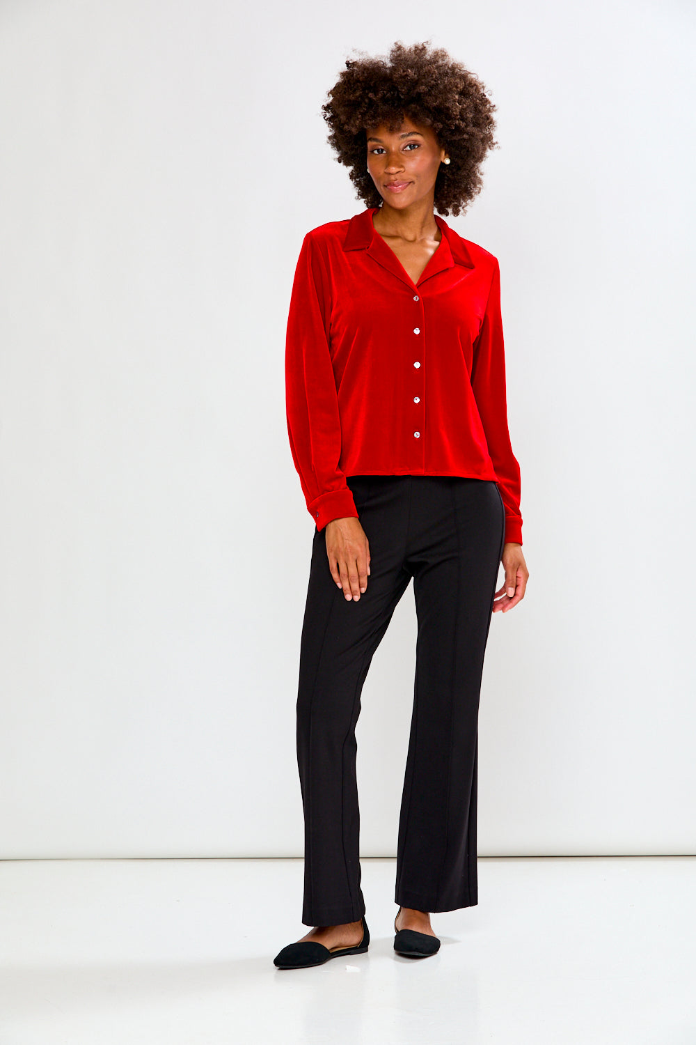 Woman wearing a red blouse and black pants on a white background
